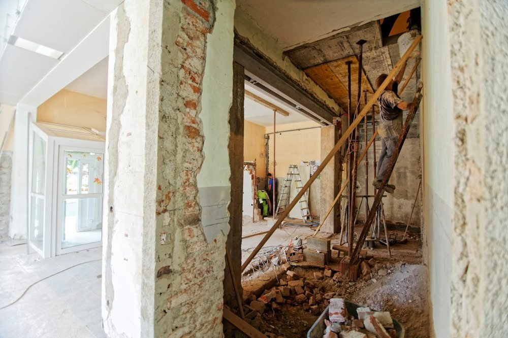 Worker and renovation debris inside a partially stripped building