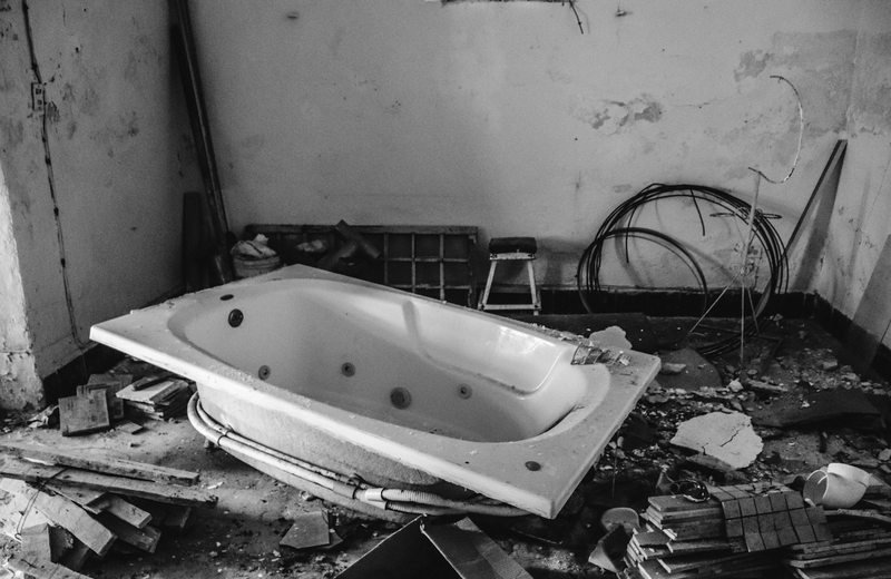 Removed bathtub and scattered materials in a stripped interior